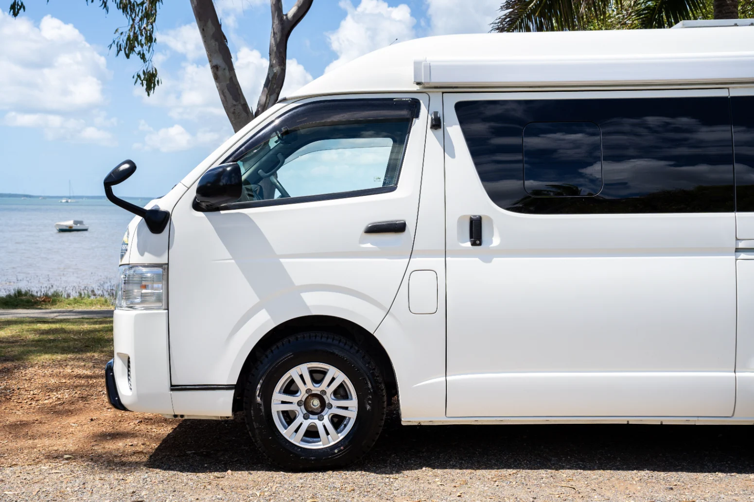 White Toyota Hiace campervan parked beside the water